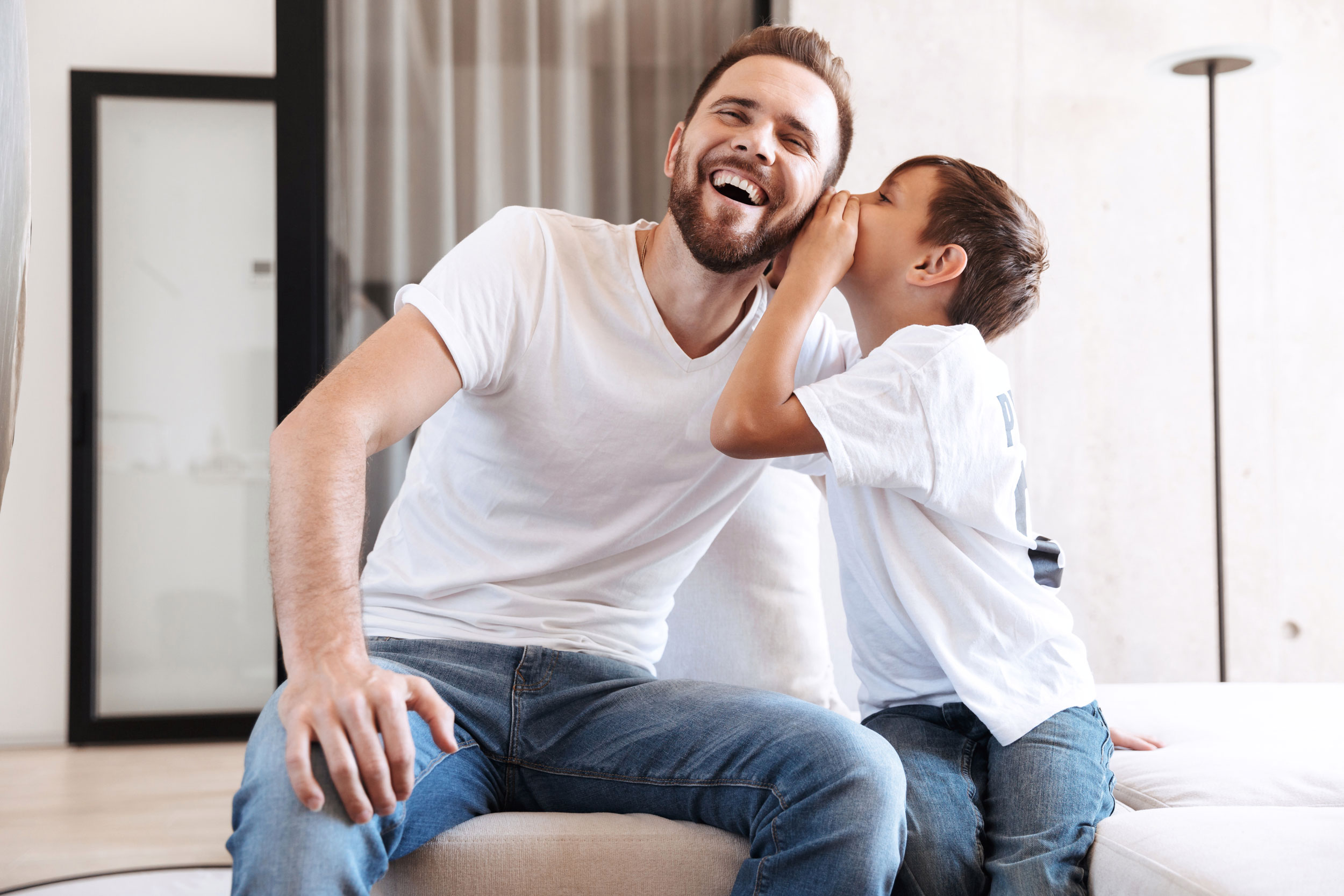 dad-laughing-as-son-whispers-in-his-ear